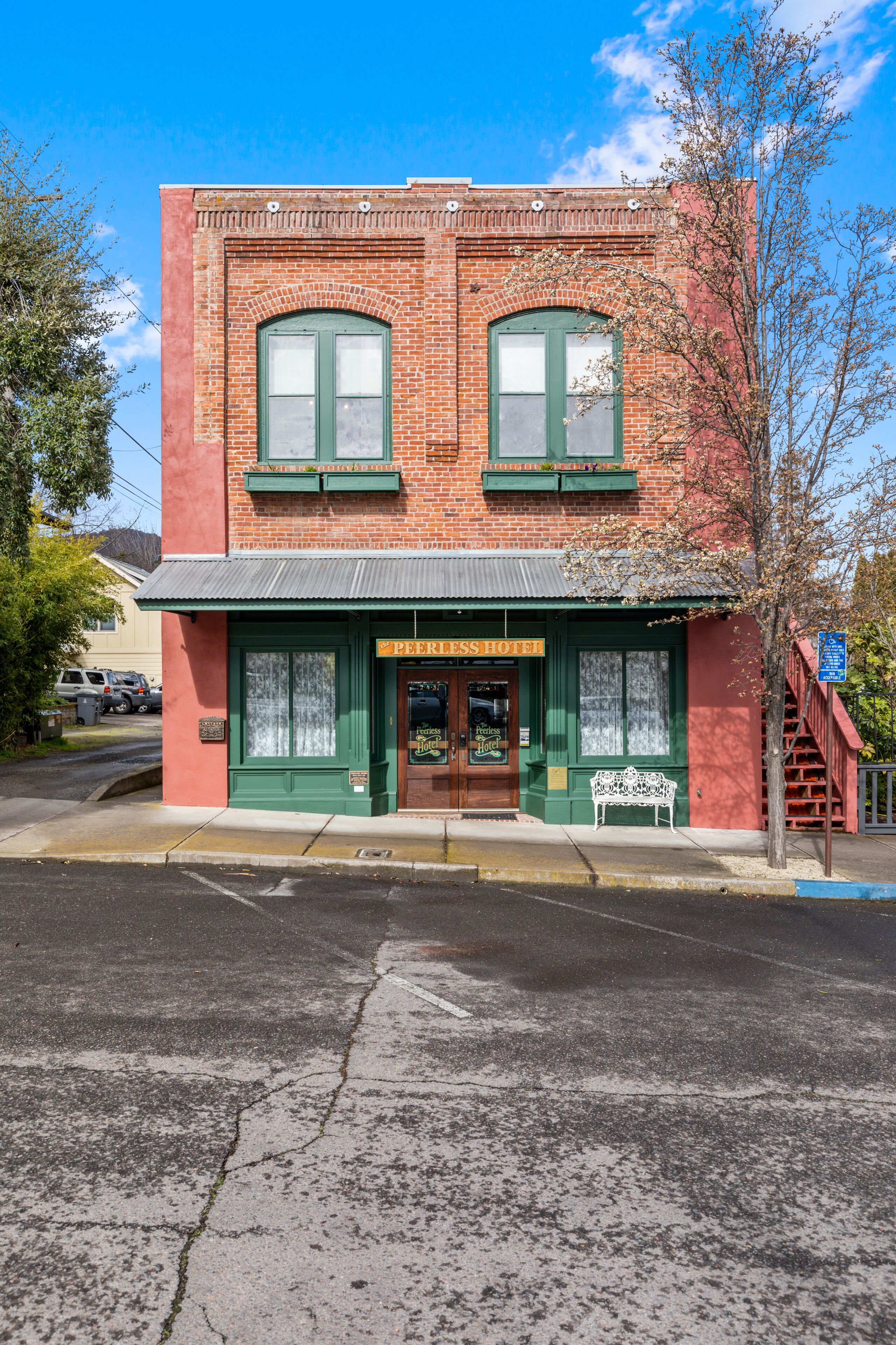 A two-story brick building with green-framed windows and a sign that reads "Hotel."