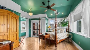 Un espacioso dormitorio con cama con dosel, muebles de madera y vistas al exterior.