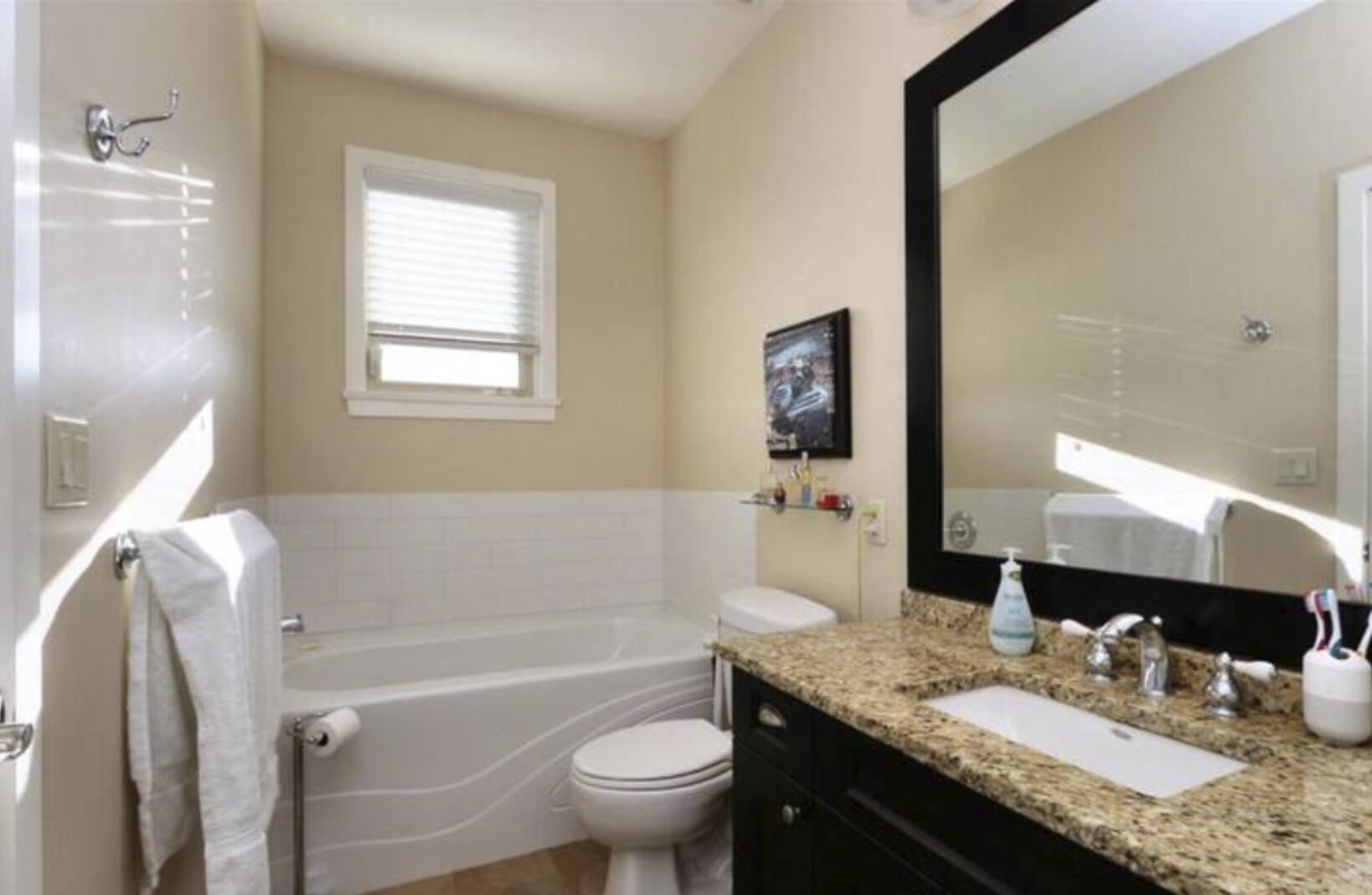 A bathroom with a bathtub, toilet, sink, and a large mirror.