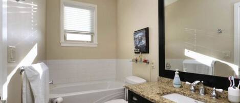 A bathroom with a bathtub, toilet, sink, and a large mirror.