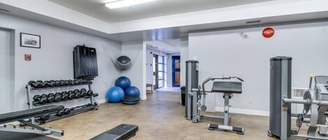 A gym with exercise equipment, dumbbells, and exercise balls.