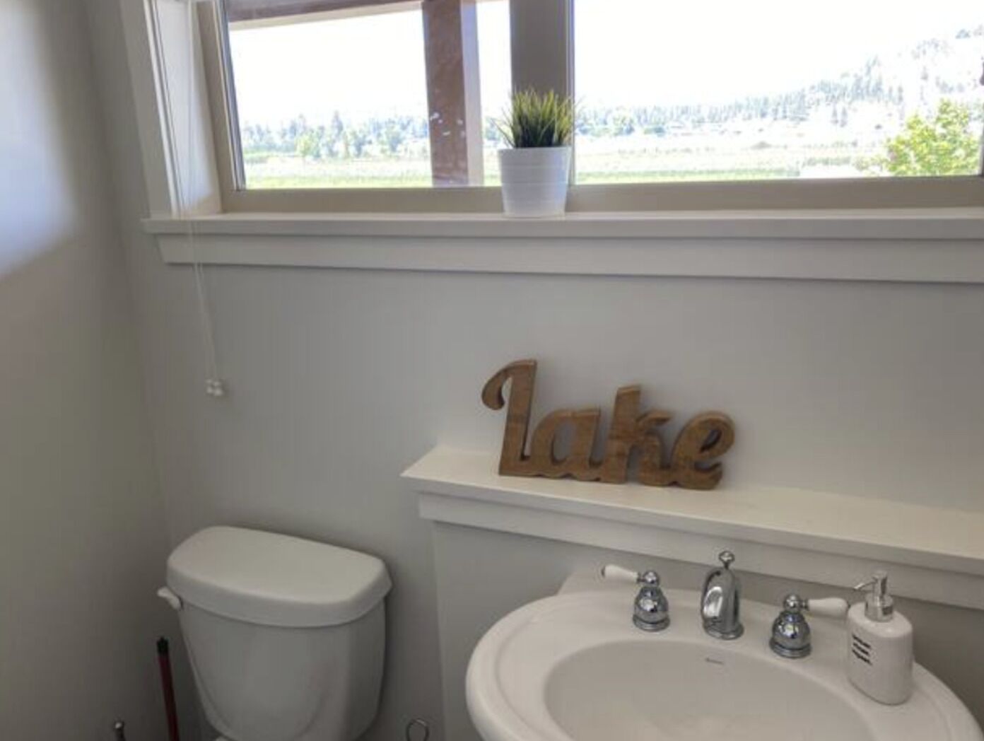 Een badkamer met toilet, wastafel en een raam met uitzicht op het landschap.