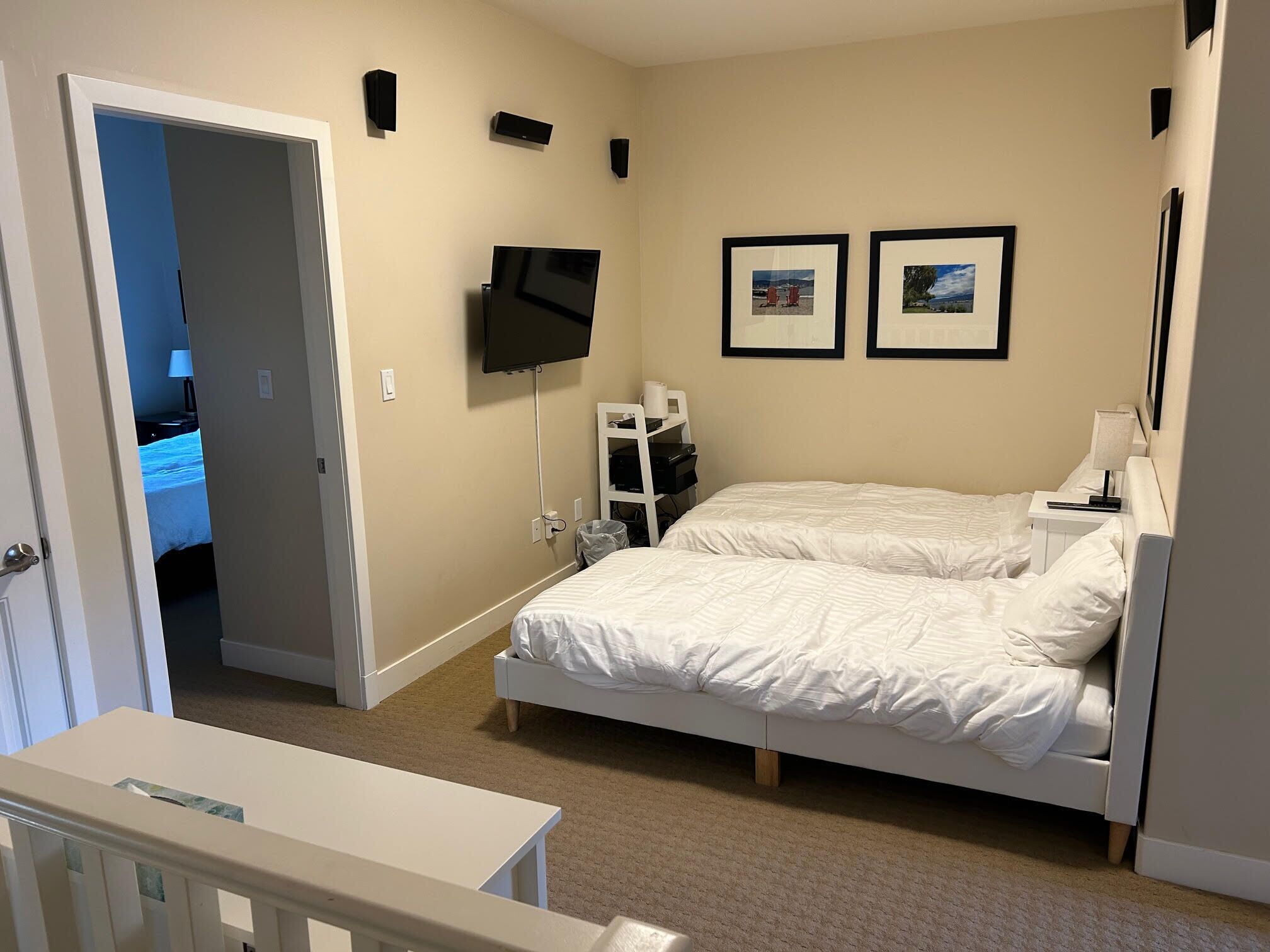 Une chambre à coucher avec un lit, un téléviseur fixé au mur et deux tableaux encadrés.