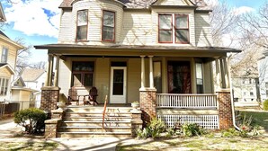 A two-story house with a front porch, a chimney, and a small front yard with steps leading to the door.