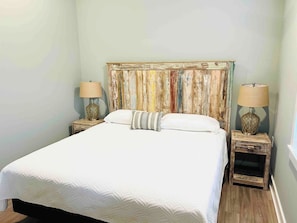 Un lit avec une couette blanche, deux tables de chevet avec des lampes et une tête de lit en bois.
