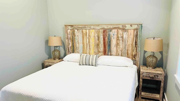 Un dormitorio con una cama grande, dos mesitas de noche con lámparas y un cabecero colorido.