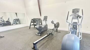 A gym with various exercise equipment including a rowing machine, an elliptical, and a stationary bike.