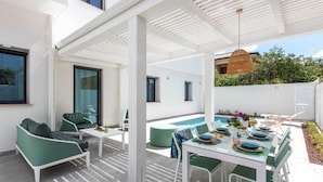 A modern outdoor patio with a pool, green furniture, and a dining table set for six. - Mondello, Villa Blu with swimming pool (7 min from the beach) (Palermo)