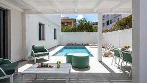 A modern outdoor patio with a pool, green furniture, and a white ceiling structure. - Mondello, Villa Blu with swimming pool (7 min from the beach) (Palermo)