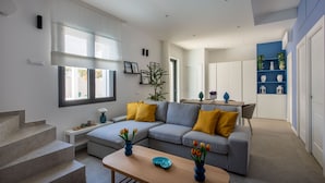 A modern living room with a grey sectional sofa, yellow cushions, a wooden coffee table, and a staircase leading to another level. - Mondello, Villa Blu with swimming pool (7 min from the beach) (Palermo)