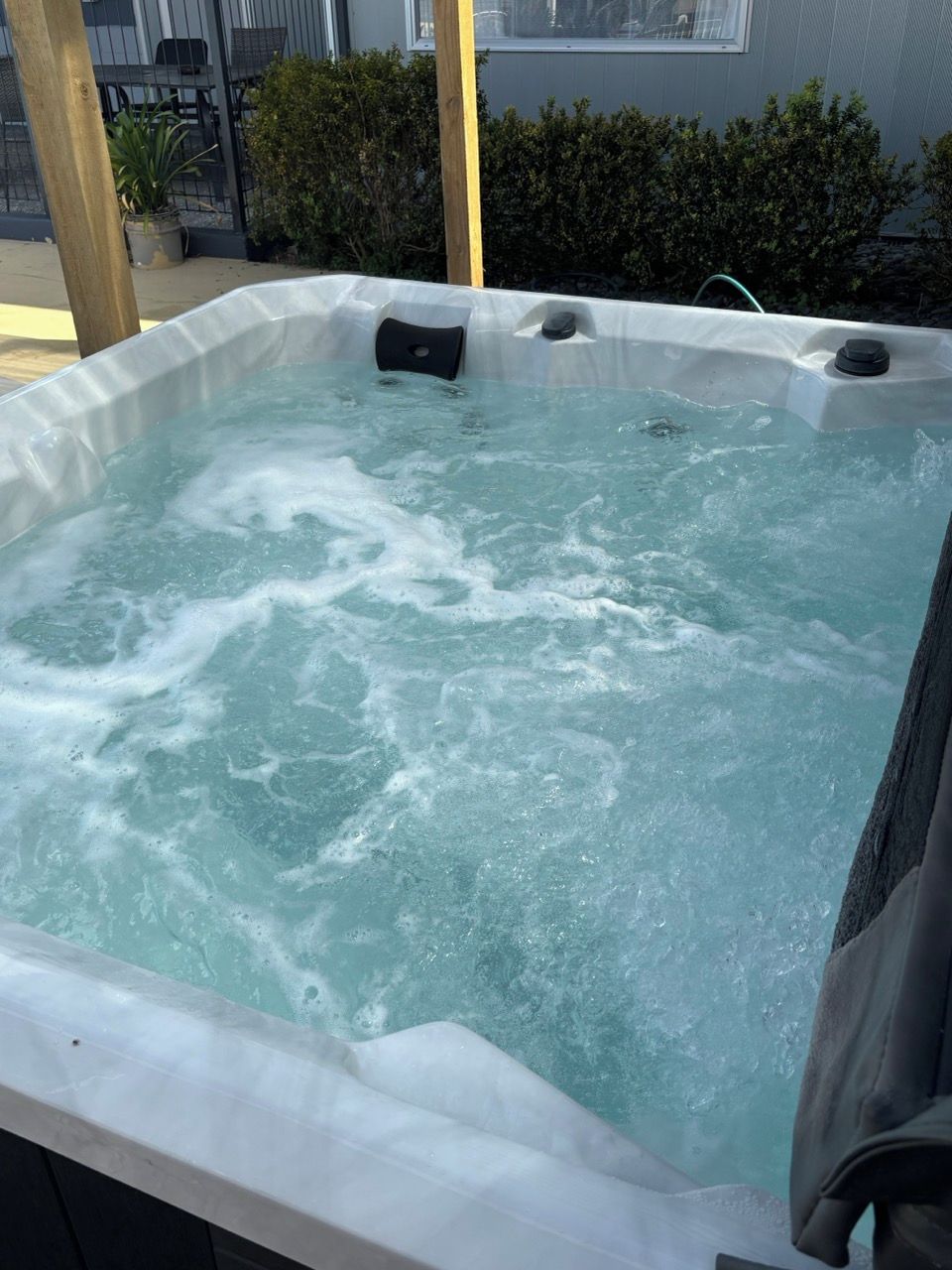 Un jacuzzi con burbujas visibles y una estructura de madera al fondo.