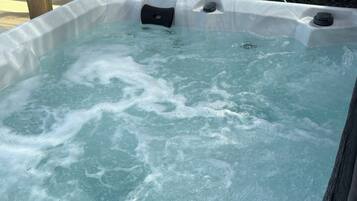 Un jacuzzi con burbujas visibles y una estructura de madera al fondo.