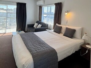 Habitación de hotel con una cama grande, un sofá, un escritorio y vistas al exterior.