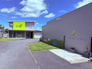 A modern building with a bright green and white facade, a reception area, and a mural welcoming visitors. - Morrinsville Motel (Morrinsville)