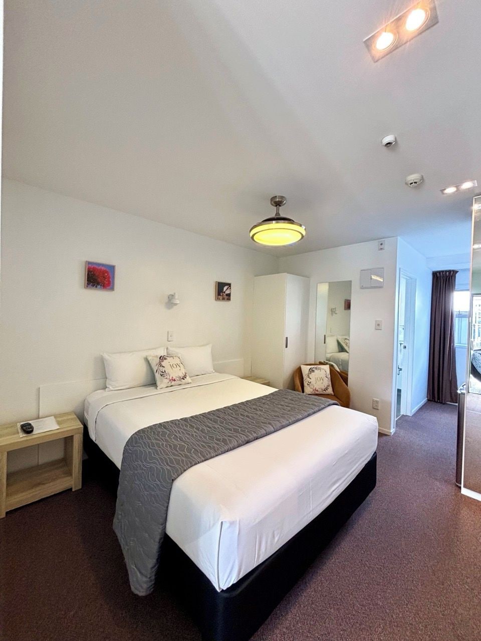 Une chambre d’hôtel avec un grand lit, des tables de chevet, une armoire et un miroir.