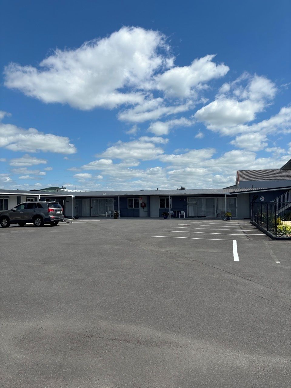 A parking lot with a building that has a flat roof and large windows.
