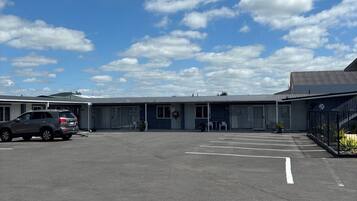 A parking lot with a building that has a flat roof and large windows.