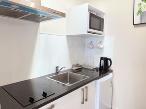 A compact kitchen with a built-in microwave, a sink, and a coffee maker. - Morrinsville Motel (Morrinsville)