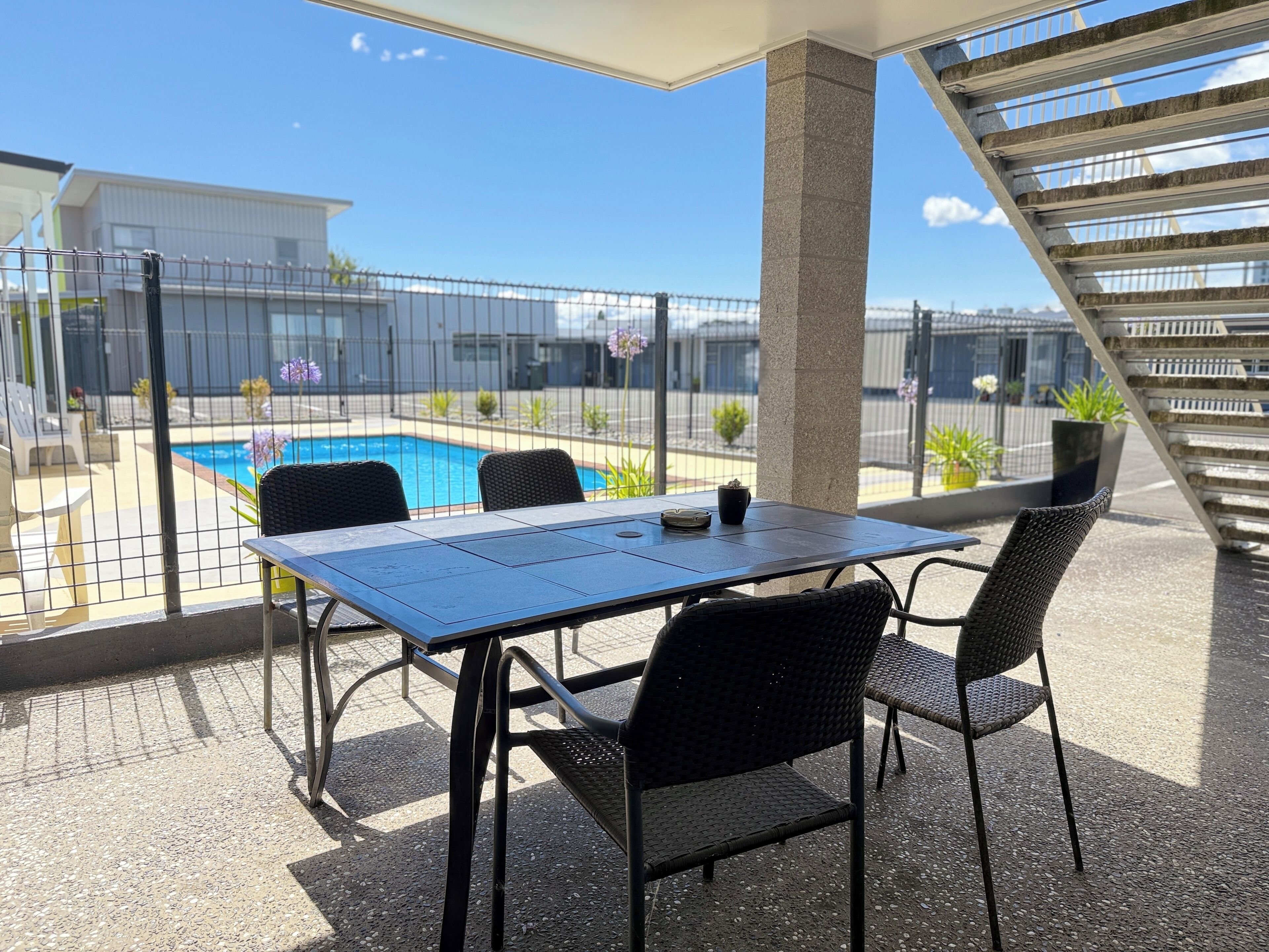 Un patio con mesa y sillas, una piscina y una escalera.