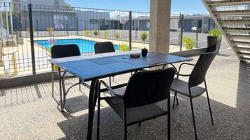 Un patio con mesa y sillas, una piscina y una escalera.