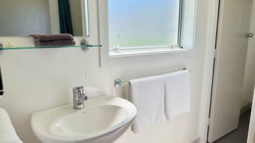 A bathroom with a white sink, a mirror, and a window.