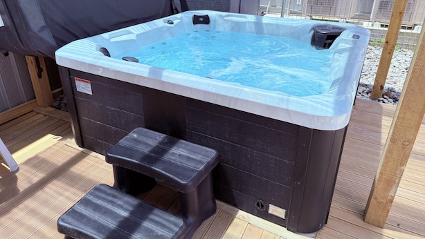 A hot tub with a wooden deck and a small step stool. - Morrinsville Motel (Morrinsville)