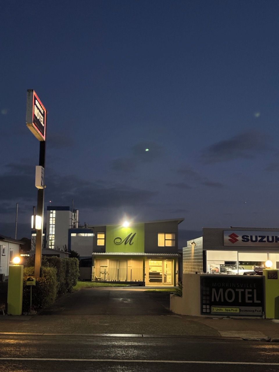Un motel con un letrero visible, un concesionario Suzuki y un cielo despejado.