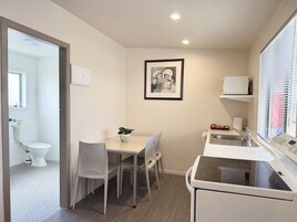Cocina compacta con comedor, estufa blanca y un cuadro en la pared.