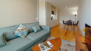 A modern living room with a sofa, coffee table, and dining area. - Legacy Oporto Design Apartment G by Vacationy (Porto)