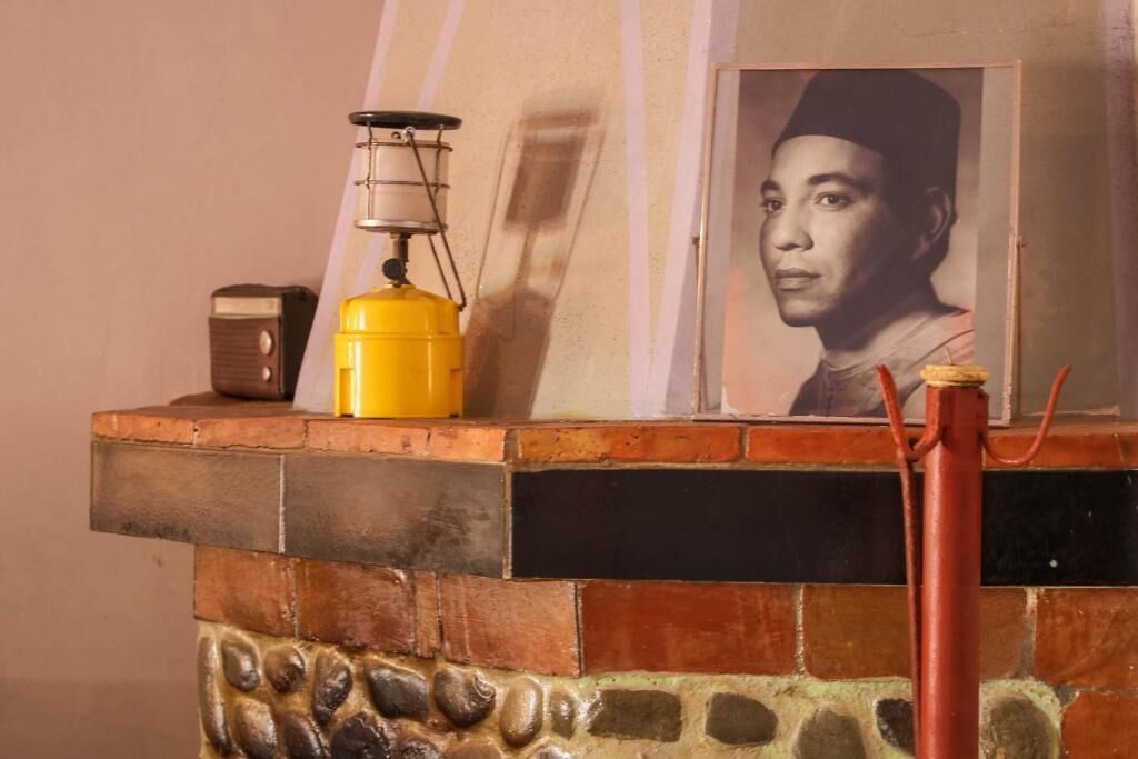 A tiled fireplace with a yellow lantern and a framed picture above it.
