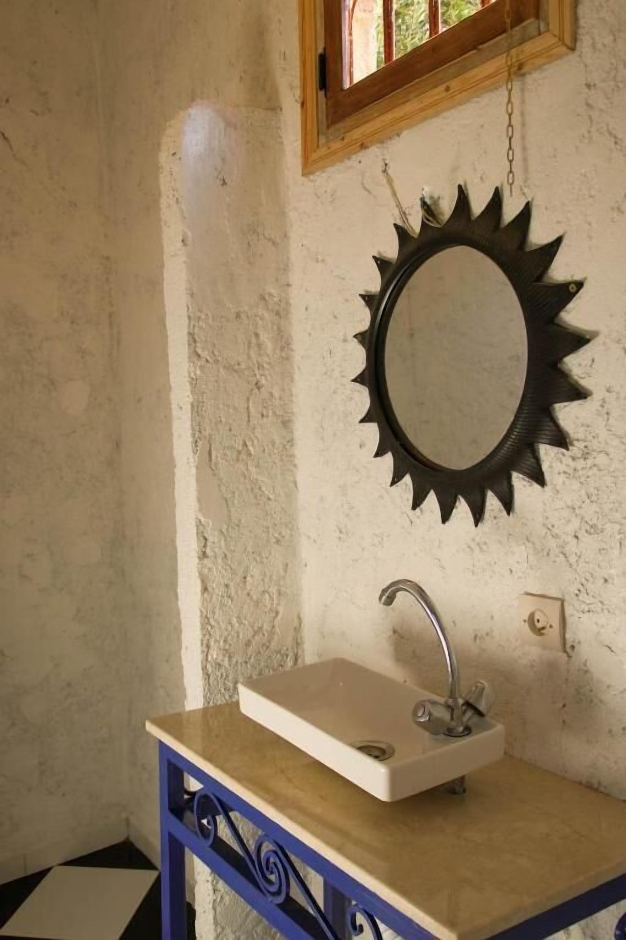 Een badkamer met een wastafel, spiegel en raam.
