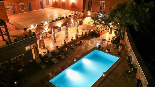 Una piscina al aire libre con zonas de descanso alrededor y plantas en macetas.