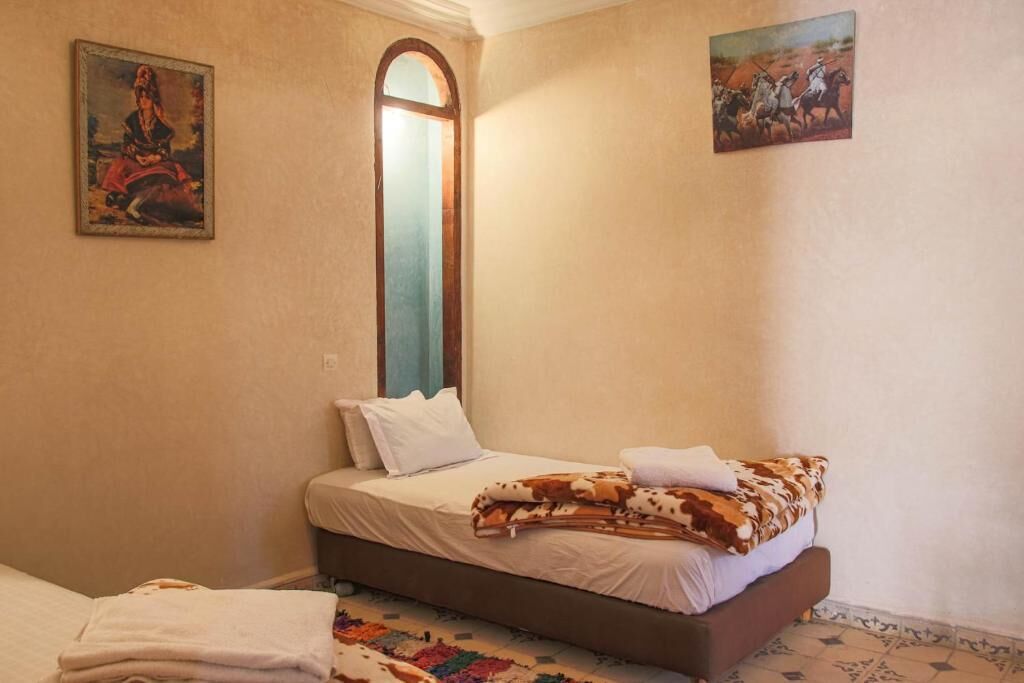 Ein Schlafzimmer mit einem Bett, einem Fenster und zwei Bildern an den Wänden.