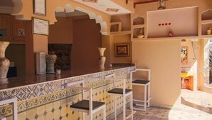 Zona de bar con salpicadero de azulejos, taburetes blancos y jarrones decorativos.