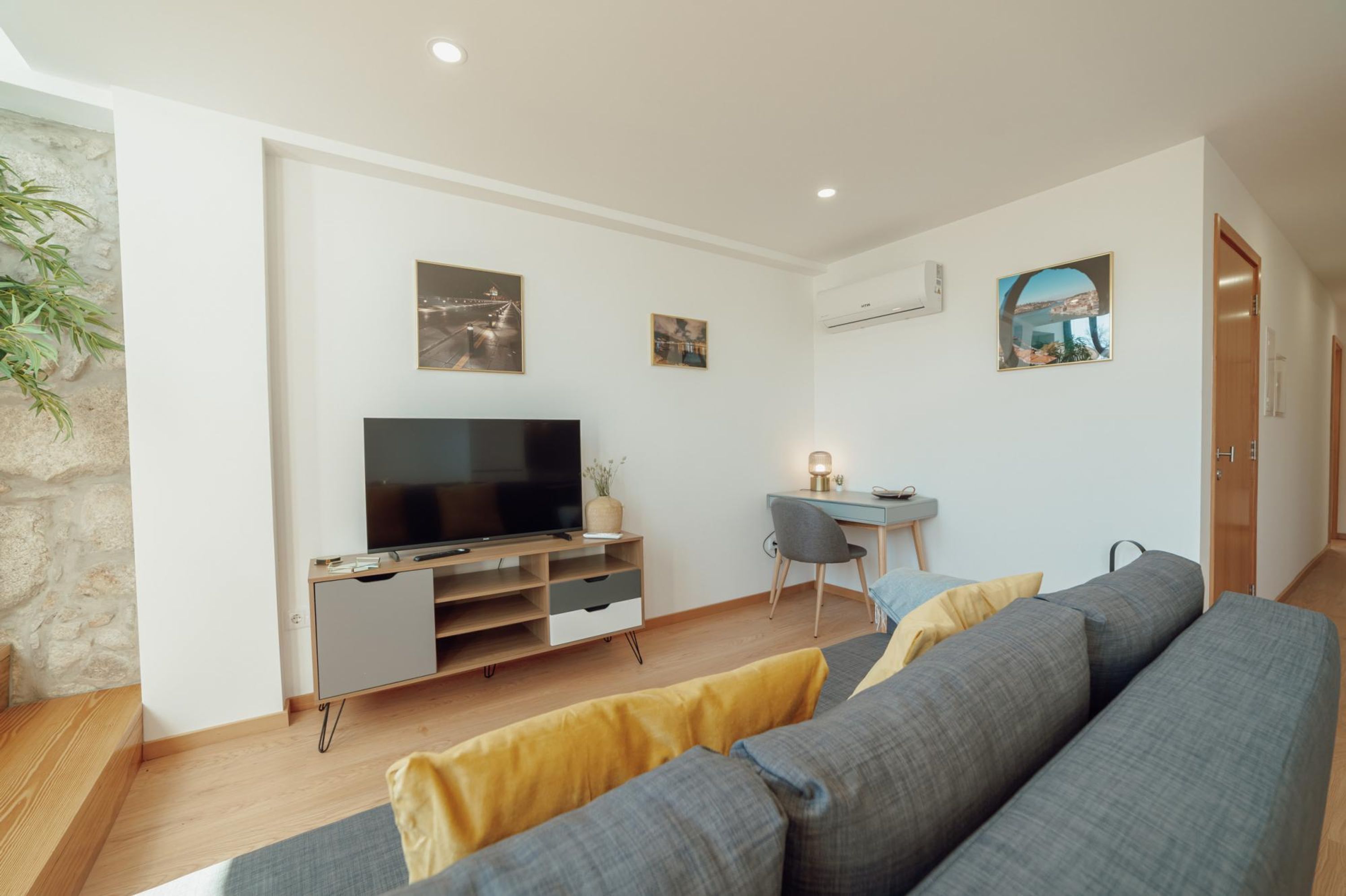 A modern living room with a flat-screen TV, a desk, and a sofa.