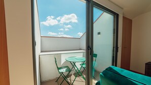 A balcony with a glass door, a small table, and two chairs.