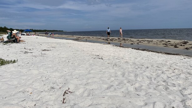 A beach with a sandy shore, a few people walking, and a clear sky. - Reel Em Inn (Carrabelle)