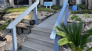 A building with a stone facade, outdoor seating, and a pathway leading to the entrance. - Reel Em Inn (Carrabelle)