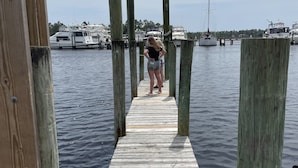 A wooden dock extending into calm water with boats docked in the background. - Reel Em Inn (Carrabelle)