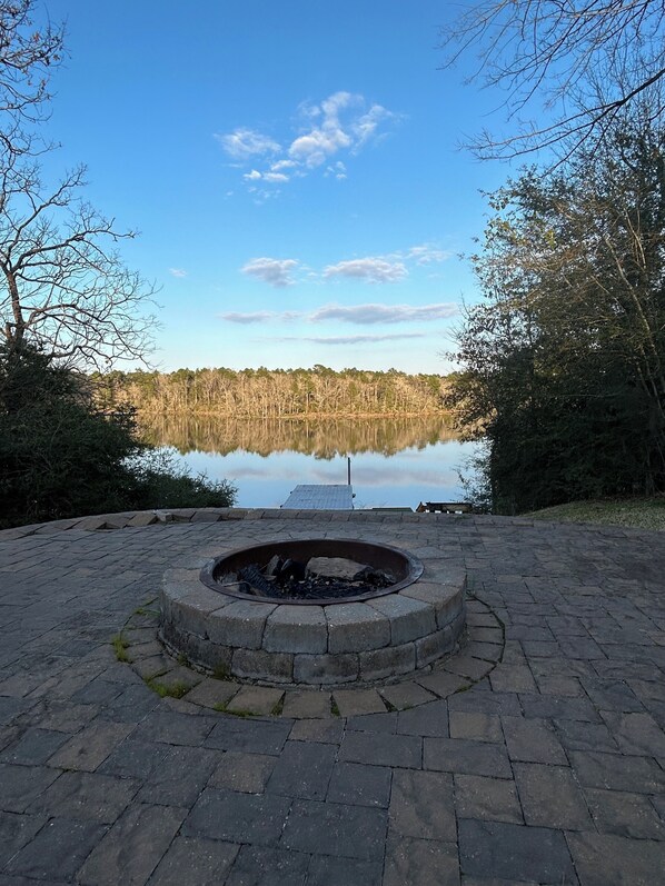 Un foyer en pierre dans un parc, avec vue sur un lac et des arbres.