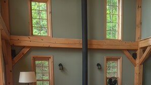 Ein gemütliches Wohnzimmer mit Kamin, Holzbalken und großen Fenstern.