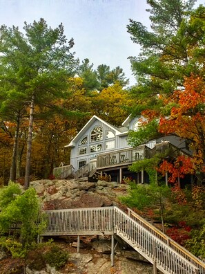 Ein Haus mit einer Treppe, die zu einer Terrasse führt, umgeben von Bäumen und Felsen.