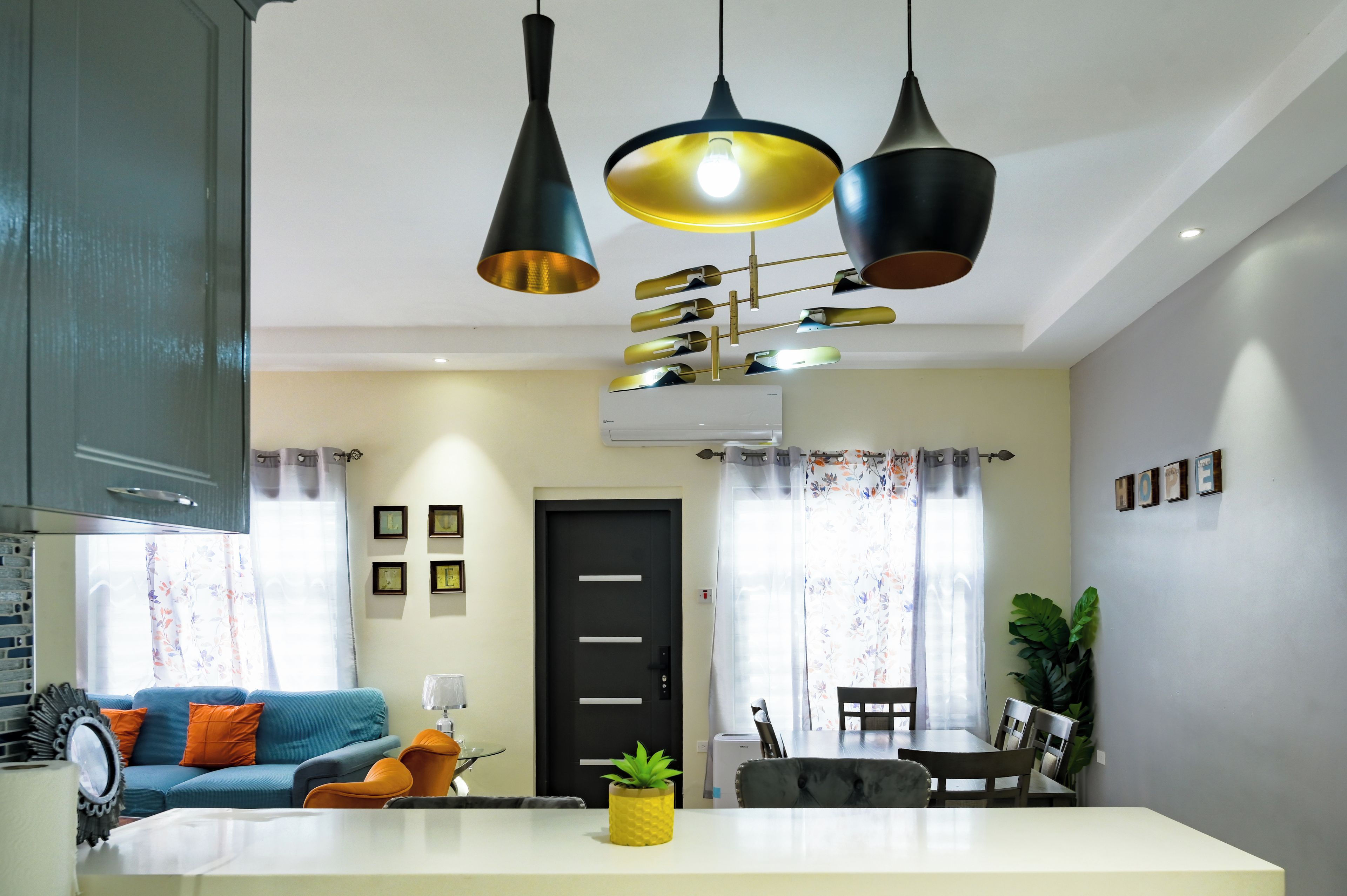 A modern living room with a blue sofa, a dining table, and a kitchen area with a stove.