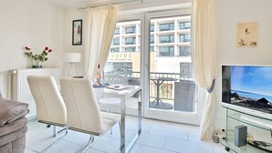 A modern hotel room with a balcony, a dining area, and a TV. - Seebrücke Appartement 14 - Seebrücke (Scharbeutz)