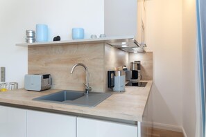 A modern kitchen with a stainless steel sink, a toaster, a coffee maker, and a kettle on the countertop.