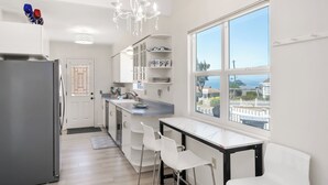 Une cuisine moderne équipée d’un réfrigérateur, de chaises blanches, d’une table à manger et d’une grande fenêtre offrant une belle vue.