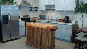 Cocina moderna con una isla central, electrodomésticos de acero inoxidable, armarios azul claro y encimera de madera.