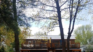 Un edificio de dos pisos con fachada de madera y un balcón. Hay una mesa de picnic al frente.
