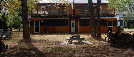 A two-story building with a wooden exterior and a balcony. There is a picnic table in front of the building.