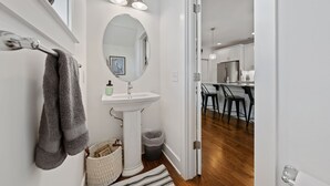 Une salle de bain moderne avec un lavabo sur colonne blanc, un grand miroir et un porte-serviettes.